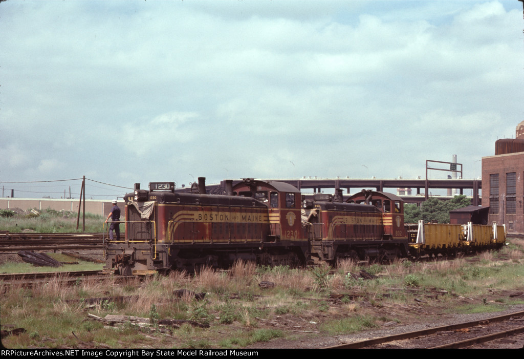 BM 1230 & BM 802 haul welded rail for the MBTA Green Line 'D' Branch past Boston Engine Terminal